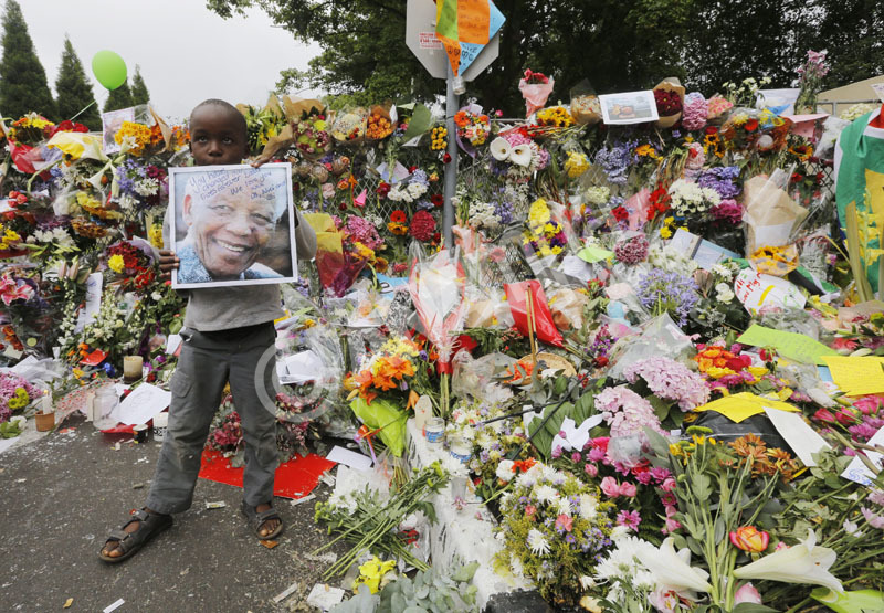  A young boy stands in front of a massive wall of flowers and condolences offered by some of the thousands of mourners outside the house of the late South African president Nelson Mandela in Johannesburg, South Africa, 07 December 2013. Nobel Peace Prize winner Nelson Mandela died at age 95, in Johannesburg, South Africa, on 05 December 2013. A former lawyer, Mandela was the first black President of South Africa voted into power after the countries first free and fair democratic elections that witnessed the end of the Apartheid system in 1994. Mandela was founding member of the ANC (African National Congress) and anti-apartheid activist who served 27 years in prison, spending many of these years on Robben Island. In South Africa, Mandela is often known as Tata Madiba, an honorary title adopted by elders of Mandela