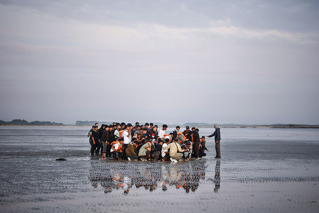  Migrants wait on a beach to board an inflatable dinghy boat to cross the English Channel, in Gravelines, northern France EPA/YOAN VALAT