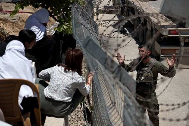 Druze people speak to an Israeli soldier through the border fence at the ceasefire line between Golan Heights and Syria, near the Druze village of Majdal Shams, in the Golan Heights EPA/ATEF SAFADI