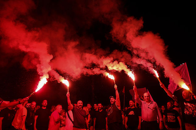 Demonstrators hold flares during a protest rally at a pier in Perama port, where the cargo ship Cosco Shipping Pisces is expected to dock, in Piraeus, Greece ΑΠΕ-ΜΠΕ/ΓΙΩΡΓΟΣ ΒΙΤΣΑΡΑΣ