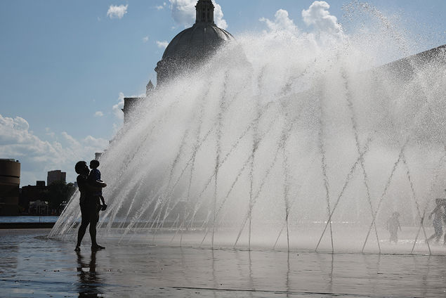 A woman carries a small child along the outer perimeter of the splash fountain at the Christian Science Plaza in Boston, Massachusetts, USA  EPA/CJ GUNTHER