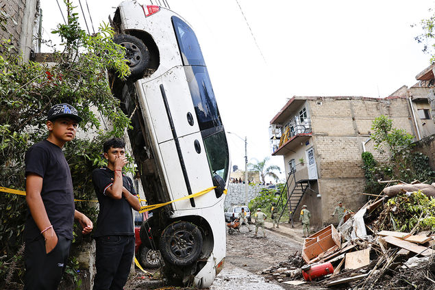 Residents stand next to a vehicle swept away by heavy rains in a neighborhood in Zapopan, Mexico EPA/FRANCISCO GUASCO