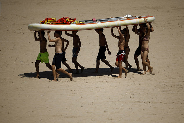 Children carry a paddle board at Malvarrosa beach in Valencia, Spain EPA/Biel Alino