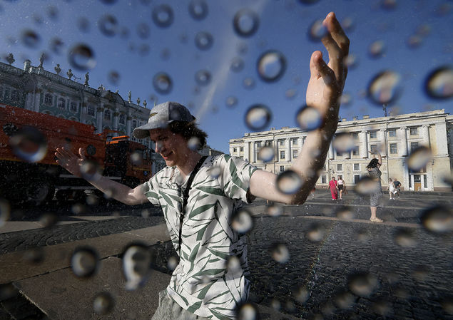 A sprinkler machine cools the air, the ground, and people during a hot day on the Dvortsovaya (Palace) Square in St. Petersburg, Russia  EPA/ANATOLY MALTSEV